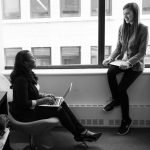 Woman in black work heels working on laptop and chatting